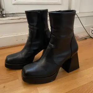 Säljer ett par svarta boots i skinnimitation i storlek 38 från Even&Odd med hög klack och dragkedja på sidan. De har en chunky design med fyrkantig tå och är perfekta för höst och vinter. Skorna är i bra skick med några mindre märken. 