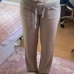 Beige/bruna mjukisbyxor med snörning - Lager 157 - Superbekväma beige/bruna mjukisbyxor i normal passform. De har en praktisk snörning i midjan och är perfekta för en avslappnad dag hemma eller en promenad. Byxorna har fickor på sidorna och är gjorda i ett mjukt material som känns skönt mot huden.