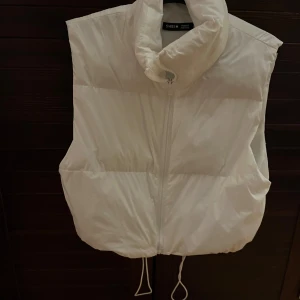 Vit dunväst från Shein - Säljer en snygg vit dunväst från Shein i storlek M. Västen har en dragkedja framtill och justerbar dragsko i nederkant för perfekt passform. Perfekt för kyliga höstdagar eller som ett extra lager under vintern. 🧥❄️