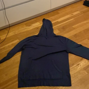 Mörkblå merinoull hoodie från Burton - Säljer en snygg mörkblå hoodie från Burton i storlek M. Perfekt för kyliga dagar med sin mjuka och bekväma passform. Den har en klassisk design med en stor ficka fram och en rymlig huva. Passar både till vardags och avslappnade tillfällen.