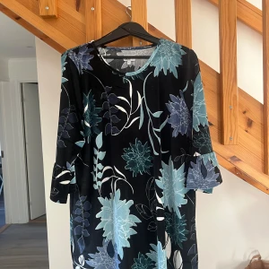 Blommig sammet klänning - Säljer en superfin klänning i sammet med ett blommigt mönster i blå och gröna toner. Klänningen har trekvartsärmar och en bekväm passform, perfekt för höst och vinter. Den är både stilren och mysig, idealisk för både vardag och festliga tillfällen❤️