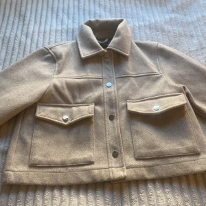Beige jacka från Zara - Säljer en snygg beige jacka från Zara i storlek XS. Perfekt för höst och vår, och den är i mycket bra skick. Passar både till vardags och lite finare tillfällen. Priset kan diskuteras 