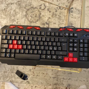 Svart och röd keyboard till Ps5-4 pc gamingdator eller vanlig dator - Säljer ett coolt gamingtangentbord i svart med röda detaljer. Tangenterna W, A, S, D och piltangenterna är röda för extra gamingkänsla. Det har en robust design och justerbara fötter för bättre ergonomi. Perfekt för långa spelsessioner! 🎮