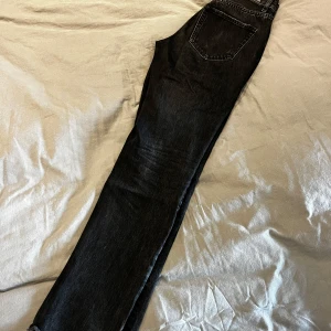 Svarta jeans med slits  - Säljer ett par svarta jeans från Gina i storlek 34. De har en klassisk design med dragkedja och knapp. Jeansen har en normal passform och är perfekta för både vardag och fest. De är i mycket bra skick och redo för en ny ägare!