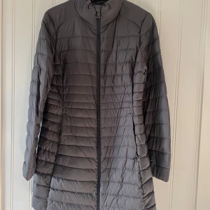 Grå dunjacka lättvikt från Polo Ralph Lauren - Säljer en snygg grå dunjacka från Polo Ralph Lauren i storlek M. Jackan har en stilren design med dragkedja framtill och är perfekt för kyliga dagar. Den är i mycket bra skick och passar både höst och vinter. Perfekt för dig som vill hålla stilen i kylan!