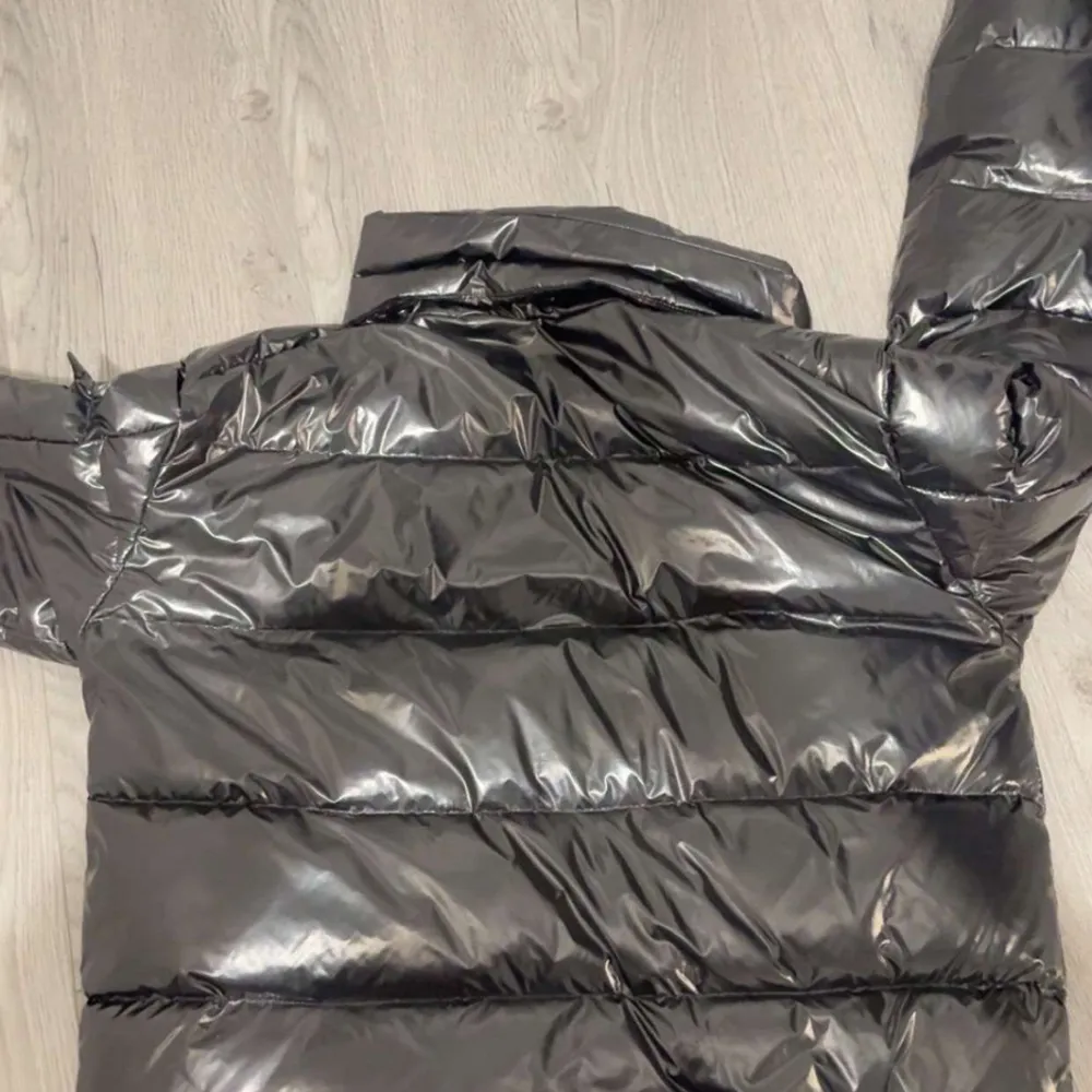 Säljer en snygg svart pufferjacka från Moncler i mycket bra skick. Jackan är perfekt för vintern med sitt quiltade mönster och långa ärmar. Den har en stilren design med Moncler-loggan broderad på ärmen. Passar perfekt för kalla dagar och håller dig varm och trendig.. Jackor.