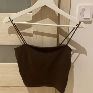 Brunt linne - Säljer ett snyggt brunt linne med smala axelband. Perfekt för sommardagar eller som ett lager under en jacka. Toppen är i ett mjukt och bekvämt material, vilket gör den idealisk för både vardag och fest.