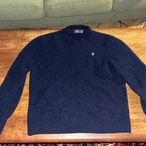 Mörkblå tröja från Morris  - Säljer en snygg mörkblå tröja från Morris . Den är i bra skick och har en stilren design med ett litet Morris emblem på bröstet. Perfekt för både höst och vinter. Tröjan har långa ärmar och ribbade kanter för en bekväm passform. Passar både till vardags och lite finare tillfällen. Storleken är igentligen L men har krympt till S/M.