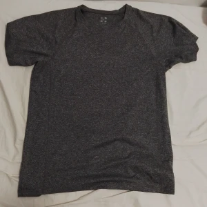 Mörkgrå t-shirt - Säljer en mörkgrå t-shirt i mycket bra skick. Den är kortärmad och har en normal passform, perfekt för både vardag och träning. Materialet känns mjukt och bekvämt mot huden. Enkelt och stilrent plagg som passar till det mesta. Perfekt för dig som gillar en minimalistisk stil.