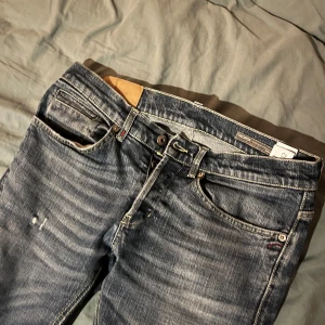 Blå jeansbyxor från Dondup - Säljer ett par snygga blå jeansbyxor från dondup. De har en klassisk femficksdesign med en knapp och dragkedja framtill. Byxorna har en lätt slitning för en cool, avslappnad look. Perfekta för både vardag och fest!