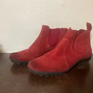 Säljer ett par snygga röda mocka boots från Think! i bra skick. De har en cool spiraldesign på sidan och robusta sulor för bra grepp. Färgen har mörknat något på tårna. Perfekta för höst och vinter, och de ger en färgklick till vilken outfit som helst. Passar både till vardags och lite finare tillfällen.