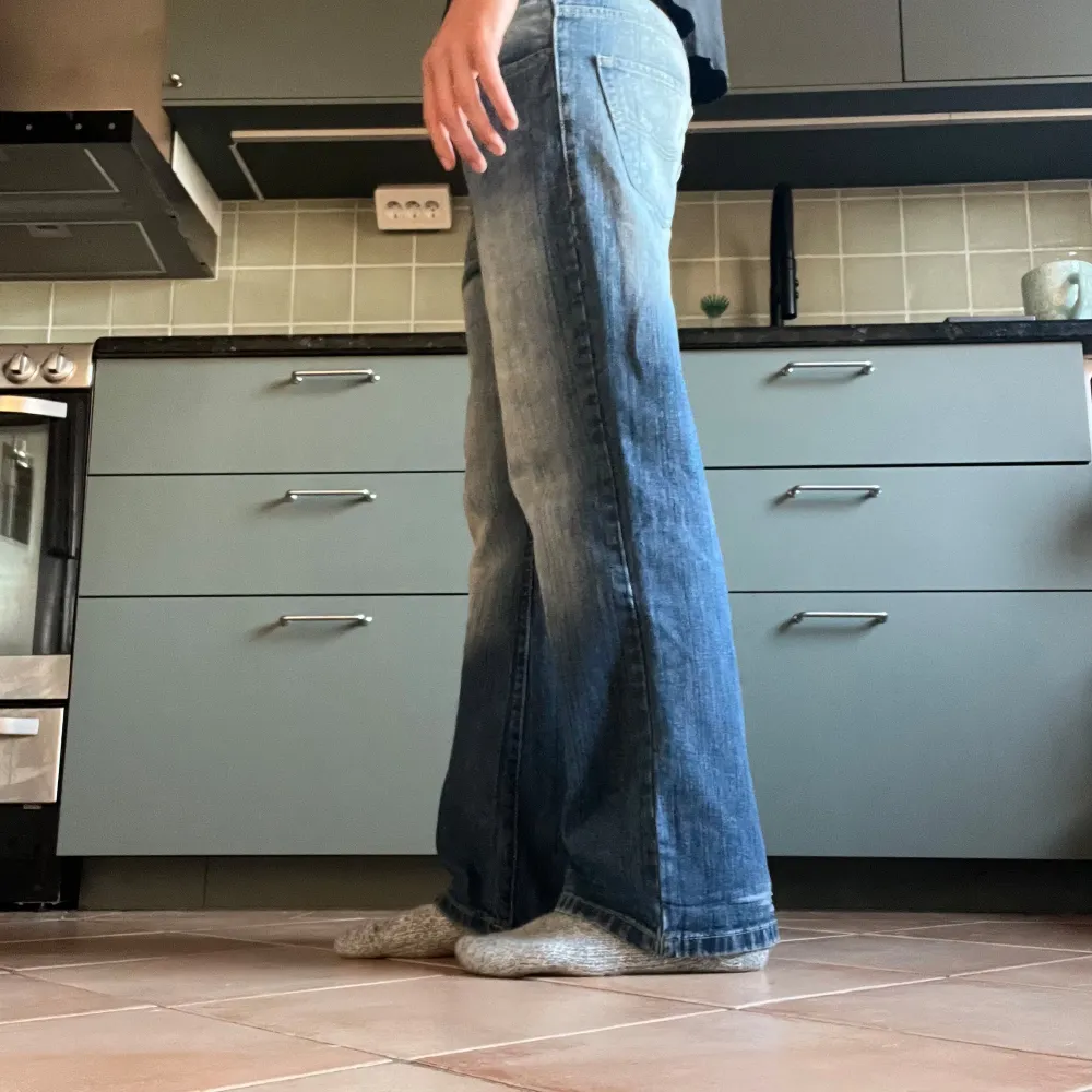 Säljer ett par blå vintage jeans i bra skick. De har en slight bootcut fit och är tillverkade i jeansmaterial. Perfekta för en avslappnad stil och passar till de flesta tillfällen. De har en snygg tvättad look och är bekväma att bära. Passar en W31 L31 (ungefär). Jeans & Byxor.