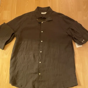 Mörkgrön linneskjorta - Säljer en stilren mörkgrön skjorta  i linne. Skjortan har en klassisk krage och knappar framtill. Perfekt för både vardag och fest! 🖤