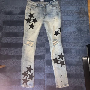 Jeans med stjärndetaljer från Reputation Studios - Snygga jeans i ljusblått från Reputation Studios med coola svarta stjärnor och slitna detaljer. Typ som amiri jeans.Perfekta för en avslappnad och trendig look. De har en normal passform och är gjorda i bekvämt denim. Perfekta för både vardag och fest!