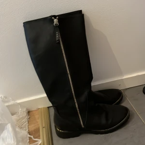 Svarta stövlar med dragkedja - Snygga svarta stövlar i skinn med en cool dragkedja på sidan. Perfekta för höst och vinter, de har en klassisk look som funkar till allt. De är i bra skick och är både stiliga och praktiska.