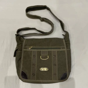 Messenger bag🤩 - messenger bag i militärgrönt med massa snygga detaljer💕ca 40x35 cm så rymmer dator. Obs dragkedjan på baksidan är sönder 