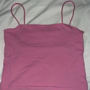 Rosa linnetopp - Säljer en söt rosa linnetopp i bomull. Perfekt för sommardagar eller som ett lager under en tröja. Den har smala axelband och en enkel design som gör den lätt att matcha med olika outfits.