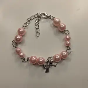 Säljer ett superfint armband med stora rosa pärlor och en söt silverfärgad rosett. Armbandet har en justerbar kedja så det passar de flesta. Perfekt för att ge en gullig touch till din outfit! 💕 Det är ett handgjort armband med rosa pärlor och silvriga detaljer, toppat med en söt, liten rosett! Perfekt för dig som vill ha något unikt. 