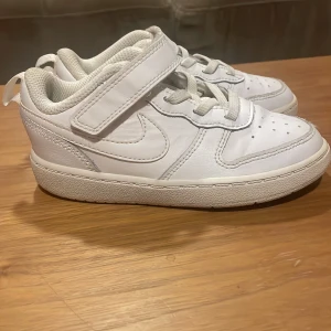 Vita sneakers från Nike - Säljer ett par vita Nike sneakers i mycket bra skick. De har både snörning och kardborreband för extra bra passform. Jag köpte de för någon månads sen tlll min bror för 600 kr men de har tyvärr inte kommit till användning. 