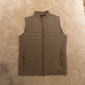 Beige brun vest - Säljer en snygg beige quiltad väst från Jack & Jones i storlek S. Perfekt för höst och vår med dragkedja framtill och en stilren design. 10/10 skick. Hör av dig om du är intresserad🤍