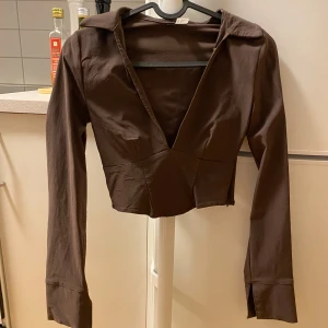 Brun blus/skjorta - En brun, croppad blus/skjorta men djup urringning. Sluter om snyggt kring kroppen🤎