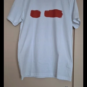 Vit t-shirt med rött tryck från Gul&Blå - Säljer en vit t-shirt från Gul&Blå med ett coolt rött tryck på framsidan. Perfekt för en avslappnad stil. T-shirten är i bomull och har en normal passform. Passar perfekt till både jeans och shorts! Helt ny och oanvänd 