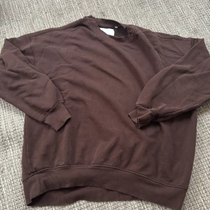 Brun sweatshirt från Junkyard - Säljer en brun sweatshirt från Junkyard i storlek S. Den är supermjuk och perfekt för en avslappnad look. Tröjan har långa ärmar och en klassisk rund halsringning. Perfekt för höst och vintermys!