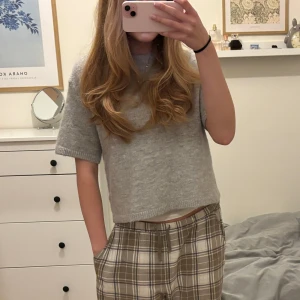 Grå stickad T-shirt - Säljer en superfin grå stickad tröja från Gina Tricot i storlek M. Den är kortärmad och har en mysig, ribbad kant vid ärmslut och nederkant. Perfekt för både vår och höst! 🩶