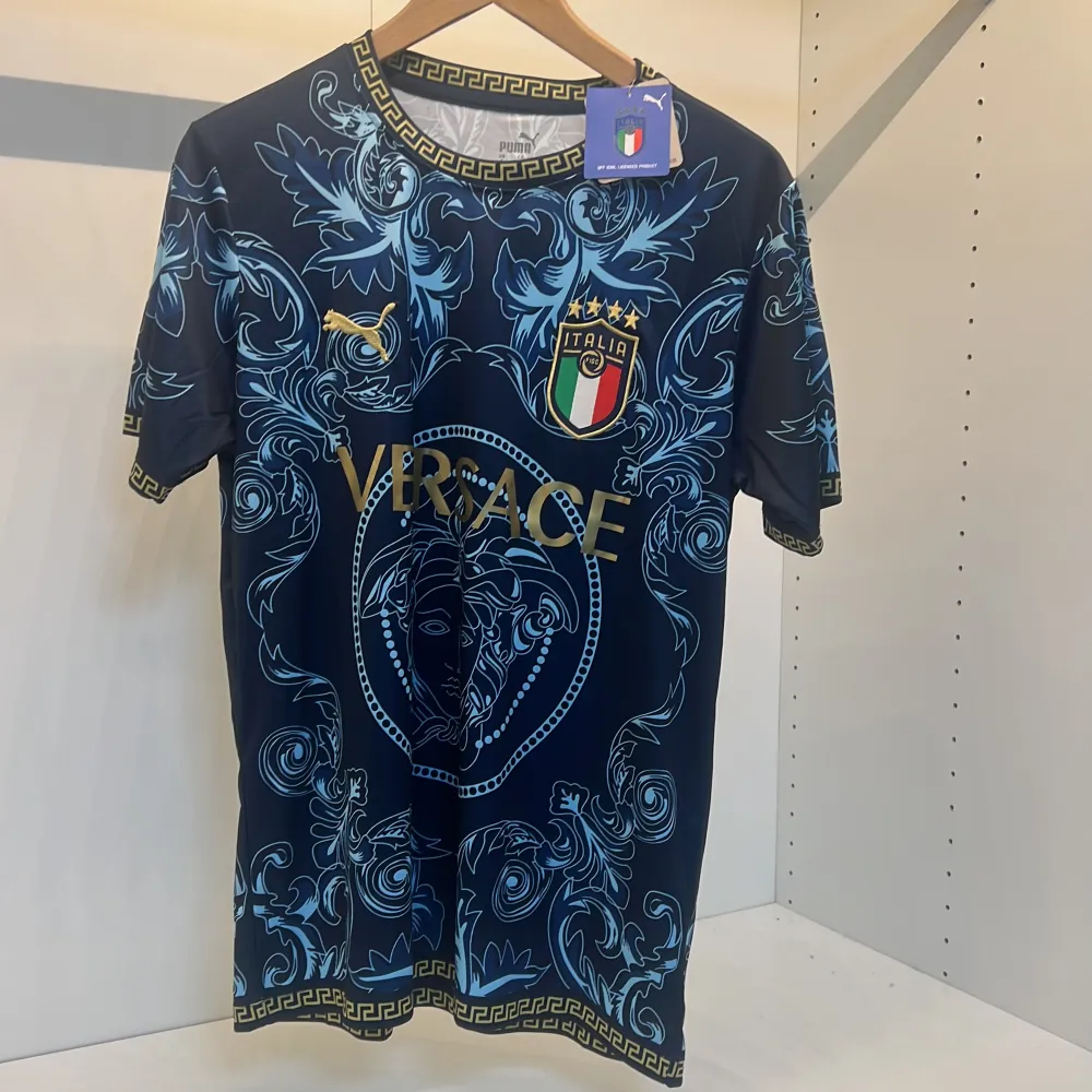 Säljer en snygg blå fotbollströja från Italien och Puma med ett detaljerat mönster i ljusblått och guld. Tröjan har korta ärmar och ett elegant mönster med italienska landslagets emblem. Perfekt för fotbollsfans som vill sticka ut! Storlek s priset kan diskuteras . T-shirts.