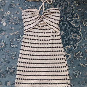 Randig stickad klänning - Säljer en superfin randig klänning i svart och vit från Pull & Bear. Den har knytning i nacken och en liten öppning framtill. Perfekt för sommardagar!