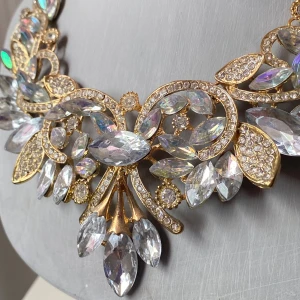 Guldigt halsband med glittriga stenar - Säljer ett fantastiskt guldigt halsband med stora, glittriga stenar i olika former. Perfekt för att göra ett statement på festen eller nyår! Halsbandet har en elegant design med både runda och droppformade stenar som fångar ljuset vackert.