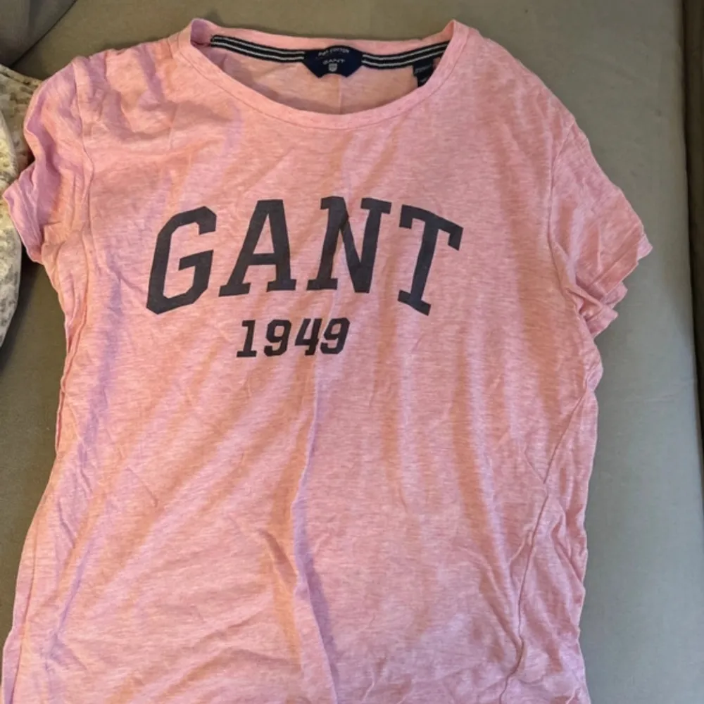 Säljer en snygg rosa t-shirt från GANT med tryck '1949' i mörkblått på framsidan. Den är kortärmad och perfekt för en avslappnad stil. Passar bra till både jeans och shorts. Perfekt för sommardagar! 🌸. T-shirts.