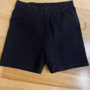 Säljer ett par enkla och bekväma svarta shorts. De har en elastisk midja för en skön passform. Perfekta för vardagsbruk eller träning. Passar bra till både sommar och vår. Saknar lapp men uppskattar den till strl 128