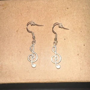Silverfärgade örhängen med G-klav - Snygga och unika silverfärgade örhängen formade som G-klavar. Perfekta för musikälskare som vill ha en personlig touch på sin stil. De är lätta och bekväma att bära hela dagen. Passar både till vardags och festliga tillfällen. 🎶