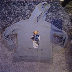 Grå Ralph lauren hoodie  - Säljer en grå Ralph lauren hoodie i mycket bra skick med Ralph lauren björnen på. Perfekt inför vintern. Storleken är junior xl vilket är ungefär xs, passar 160-170. Hör av er vid frågor!