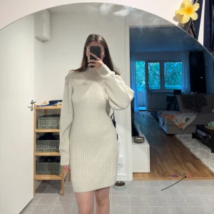 Beige stickad klänning - Säljer en supermysig beige stickad klänning i storlek M. Den har en normal passform och långa ärmar, perfekt för höst och vinter. Klänningen är ribbad och ger en stilren look. Perfekt för både vardag och festliga tillfällen!