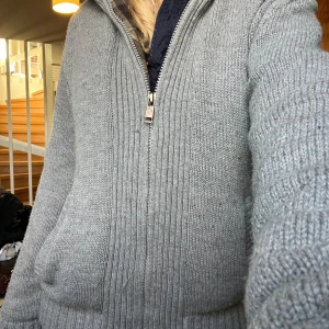 Grå stickad hoodie med dragkedja - Säljer en supermysig grå stickad hoodie med dragkedja. Väldigt tjockt material. Perfekt för både höst och vinter!