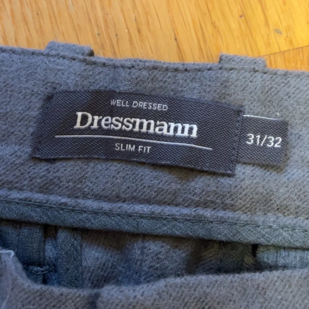 Gråa slim fit byxor från Dressmann i storlek 31/32. De är i bra skick och perfekta för både vardag och fest. Byxorna har en klassisk design med knappar och dragkedja framtill.. Jeans & Byxor.