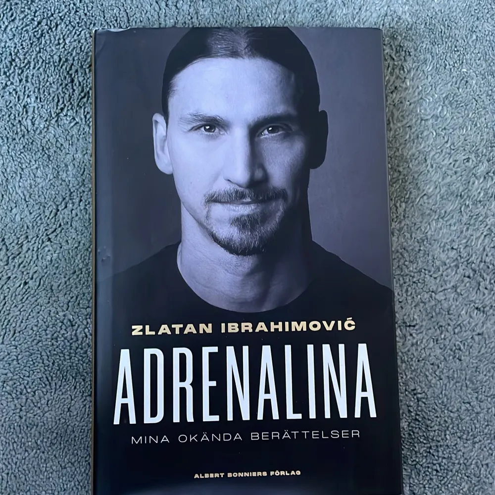 Boken 'Adrenalina: Mina okända berättelser' av Zlatan Ibrahimović, berättad för Luigi Garlando och översatt av Viveka Holm, erbjuder en inblick i Zlatans liv och karriär. Den har en stilren svartvit design med ett porträtt på framsidan och en bild av hans ryggtatueringar på baksidan. Pris diskuteras!. Böcker.