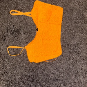 Orange topp från Zara - Säljer en snygg orange topp från Zara i stickat material. Perfekt för sommaren med sin livfulla färg och bekväma passform. Toppen har smala axelband och en enkel design som gör den lätt att matcha med olika outfits. Perfekt för både vardag och fest!