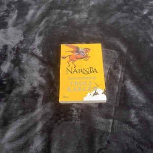 Narnia: Min morbror trollkarlen - Säljer boken 'Narnia: Min morbror trollkarlen' med ett färgglatt omslag i gult och illustration av en flygande häst. Perfekt för fantasyälskare och Narnia-fans! 📚✨