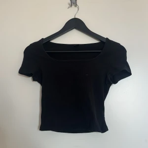 Svart croppad t-shirt - Svart topp med korta ärmar och rund halsringning. Använd, bra skick.