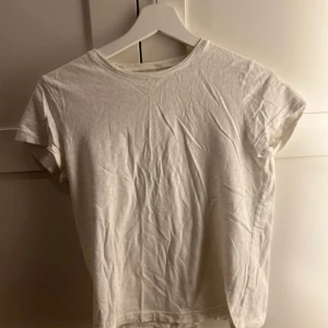 Vit t-shirt från Lindex - Säljer en klassisk vit t-shirt från Lindex i storlek 146/152. Den har en enkel design med korta ärmar och rund halsringning. Perfekt basplagg för alla tillfällen.