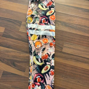 Färgglada leggings från Stronger - Snygga leggings från Stronger med ett färgglatt fruktmönster. Perfekta för att sticka ut på gymmet eller vid andra aktiviteter. De har en hög midja och är tillverkade i ett stretchigt syntetmaterial för bästa komfort.