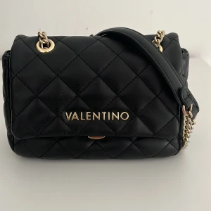 Svart axelväska från Valentino🖤 - Fin svart valentino väska köpt från zalando. Ursprungs pris är 1345kr. Färgen har gott bort lite där man stänger!  Säljer på grund av att har tröttnat på den lite🩷