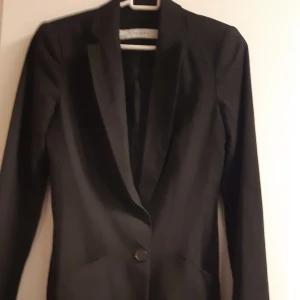 Svart Blazer från Zara - Elegant svart Blazer från Zara i storlek XS. Kavajen har en klassisk design med en knapp framtill och långa ärmar. 