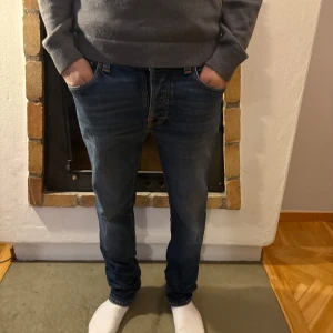 Mörkblå jeans från Nudie Jeans - Snygga mörkblå jeans från Nudie Jeans med en klassisk femficksdesign. De har en dragkedja och knapp framtill. Perfekta för en stilren look.