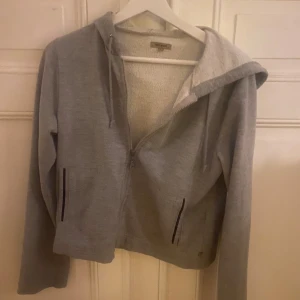 Grå hoodie med dragkedja - Säljer en mysig grå hoodie från vera moda med dragkedja och huva. Storlek M men skulle mer säga att den är s/xs 