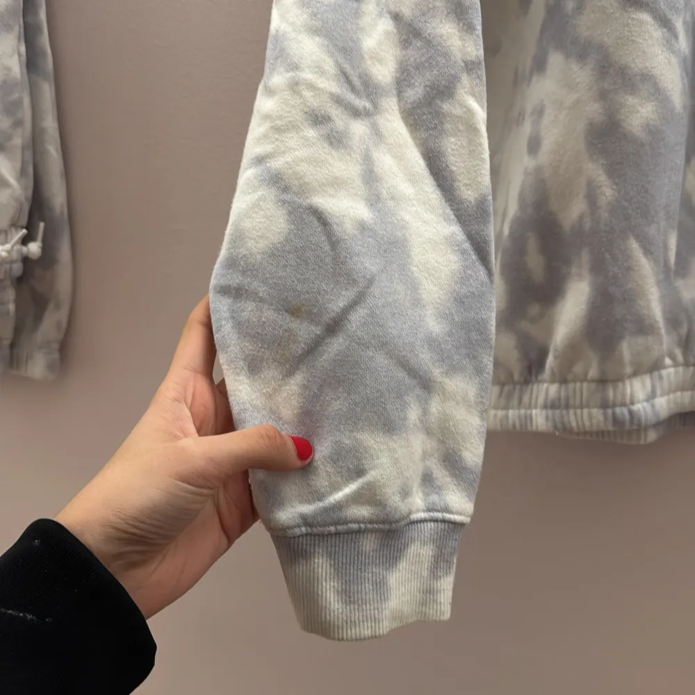 Säljer en grå och vit batikmönstrad sweatshirt med texttryck på bröstet. Tröjan har långa ärmar och ribbade muddar vid ärmslut och nederkant. Perfekt för en avslappnad stil. är det storlek 170 14 år men skulle kunna passa en Xs. på armen av tröjan så finns det en liten gul fläck som knappt syns. Neuletakit & Villapaidat.