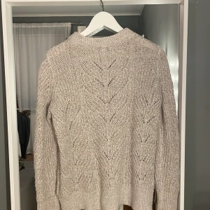 Beige stickad tröja - Mysig beige stickad tröja med ett fint mönster. Perfekt för kyliga dagar med sin varma och bekväma design. Tröjan har långa ärmar och en rund halsringning.